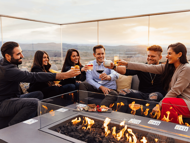 group cheers at hive & honey rooftop sitting by a firepit