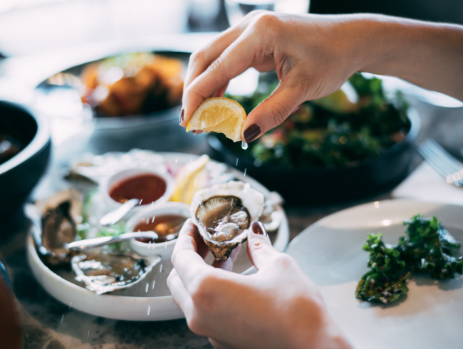 Person squeezing lemon on oyster